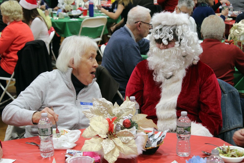 woman and boy dressed as Santa talking at dinner table