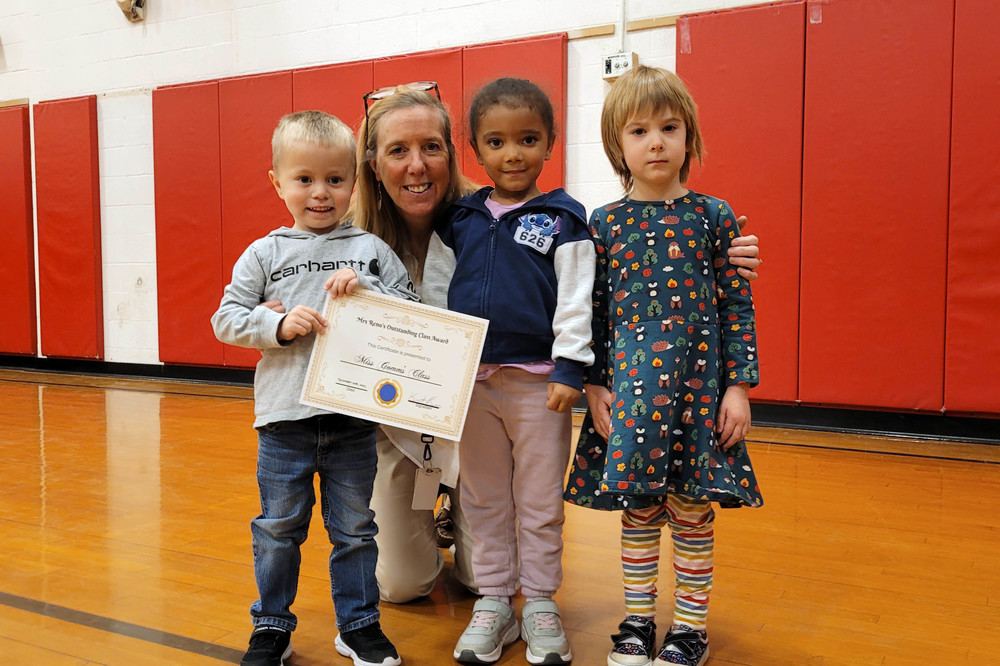 woman and three young children psoing fpr photo with certificate and lots of smiles