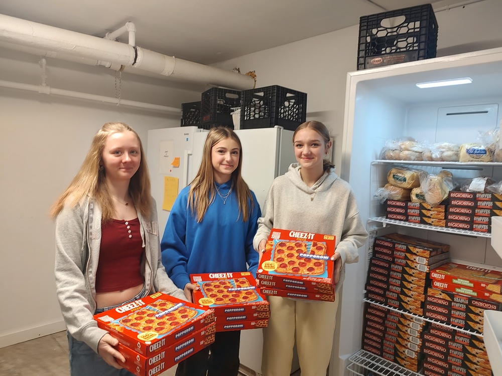 three girls holding boxed of frozen pizza