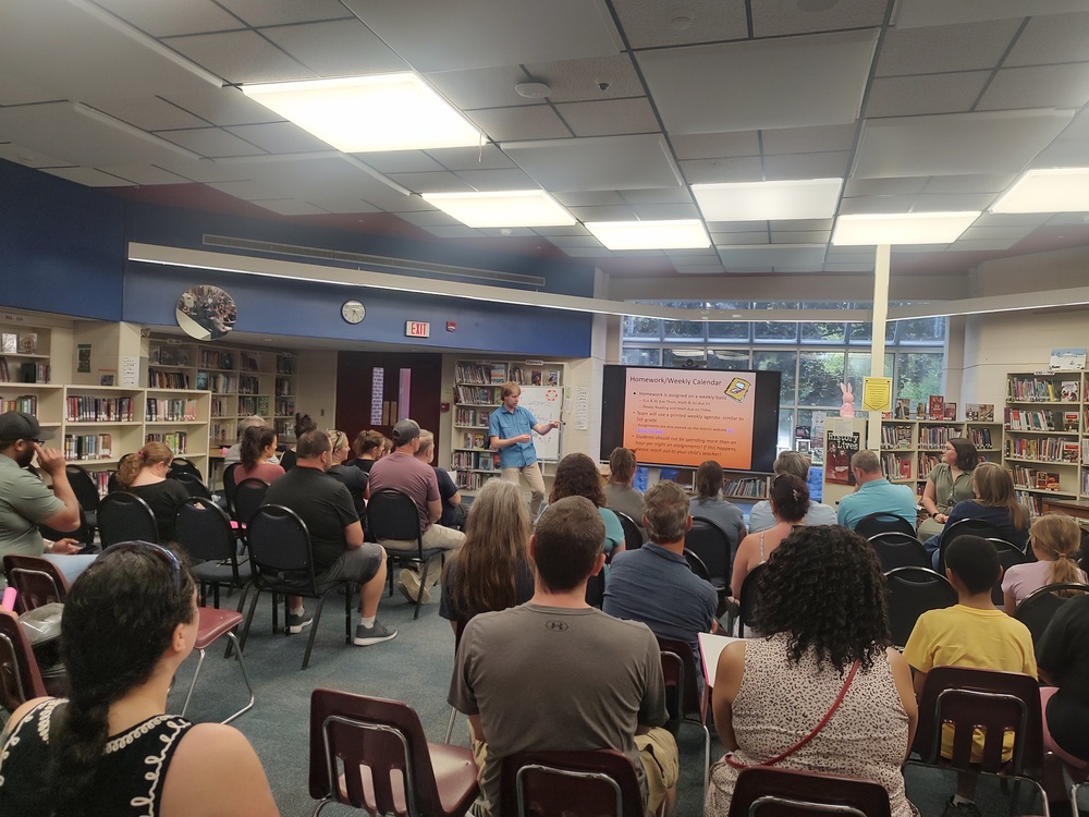 teacher give presentation to large group of seated parents