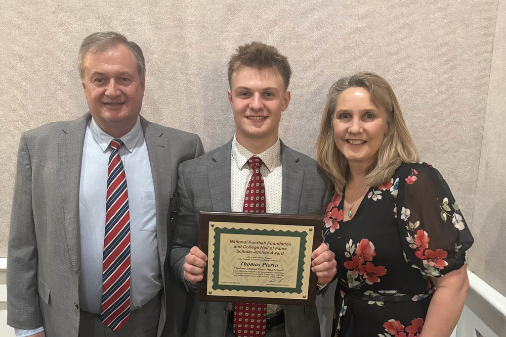 Thomas Pierro holding award plaque flanked by family members 