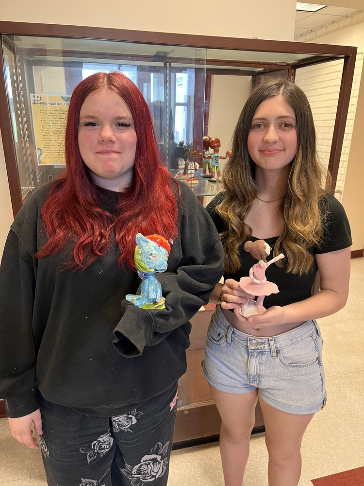 Two girls holding bobbleheads they made