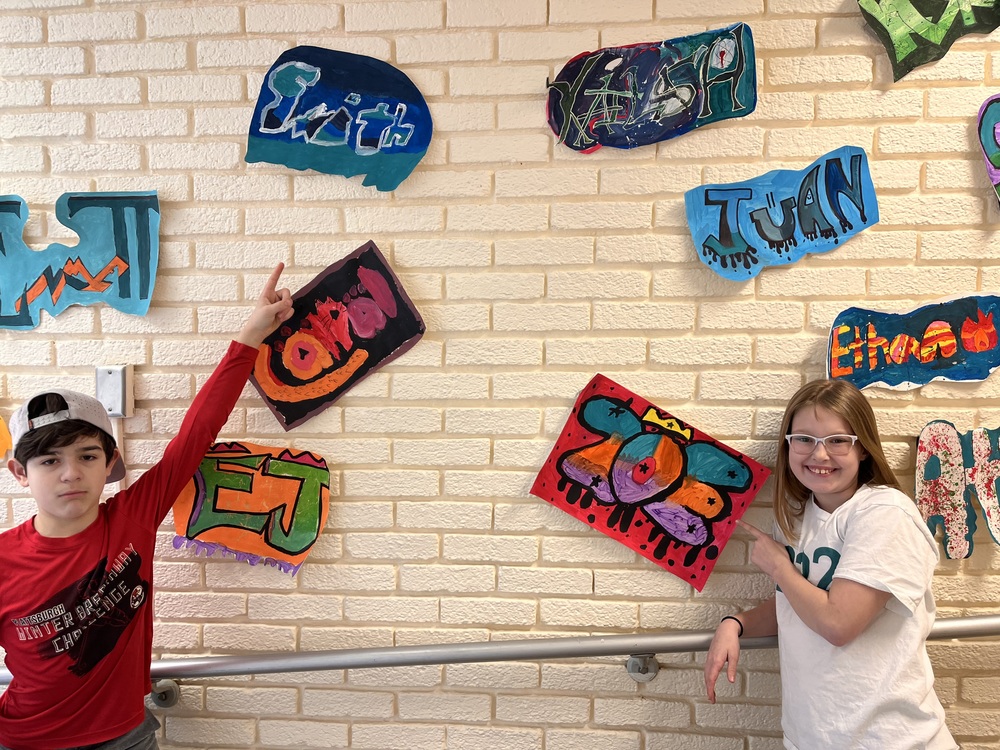 students pointing to graffiti art they made