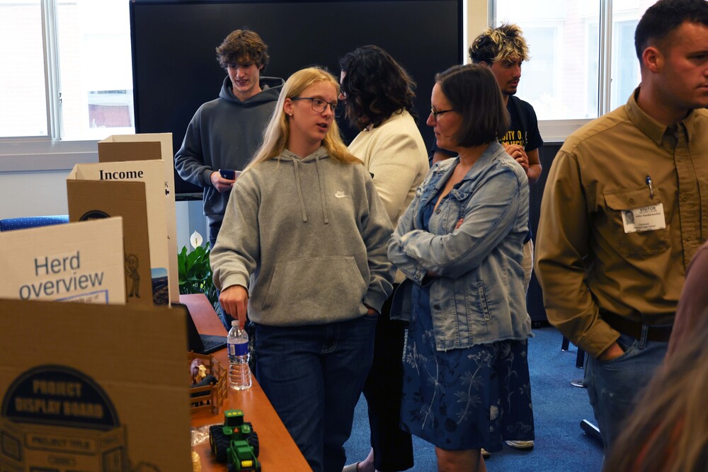 girl speaking to woman in from of posterboard display
