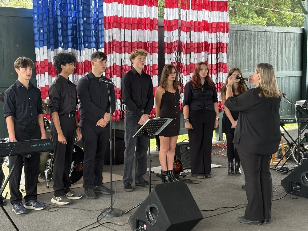 students singing in front of American Flag