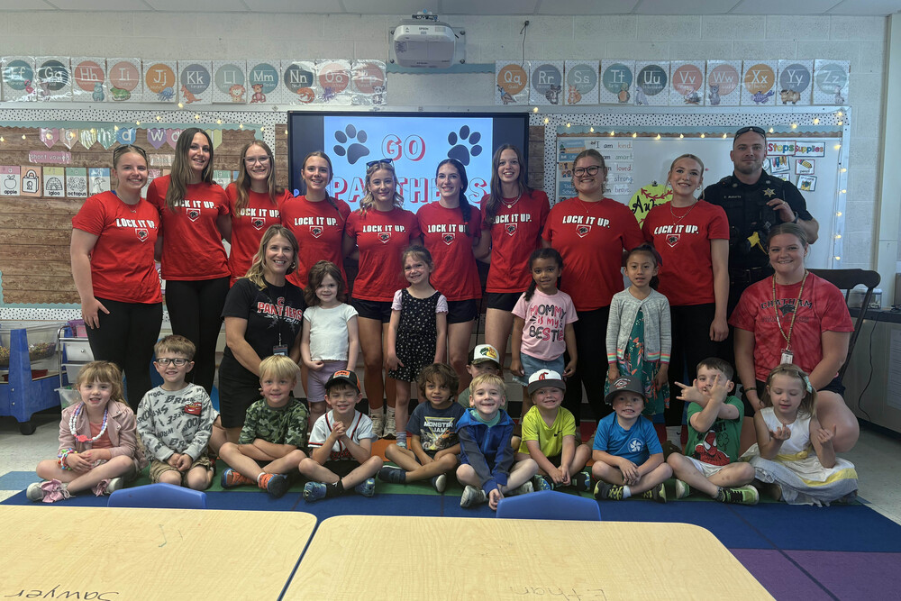 varsity softball senior team members pose for group photo with pre-k class