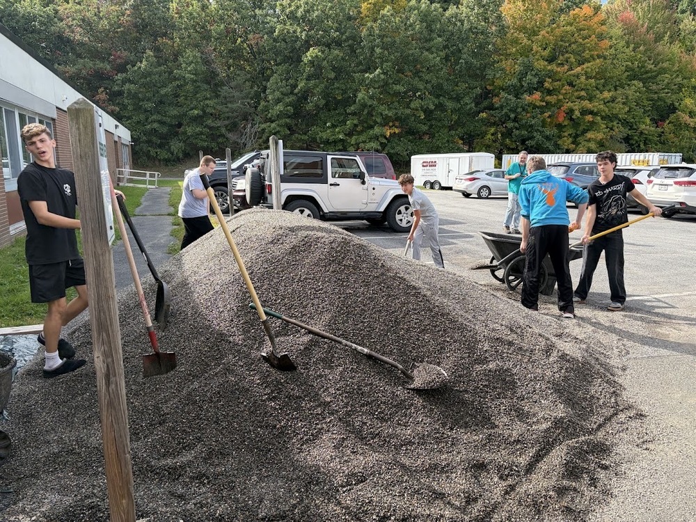 students moving big pile of peastone