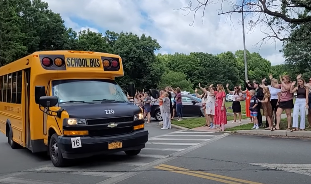teacher wave to passing school bus