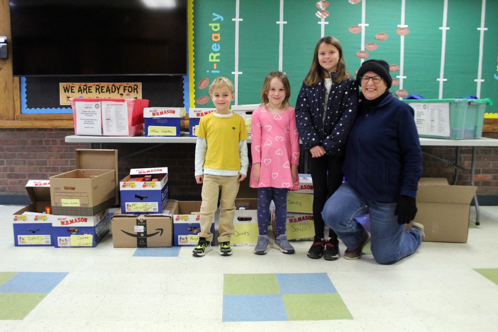 students and woman pose with boxes of  food items