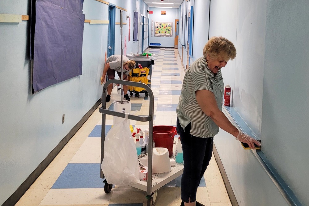 two women cleaning hallway walls