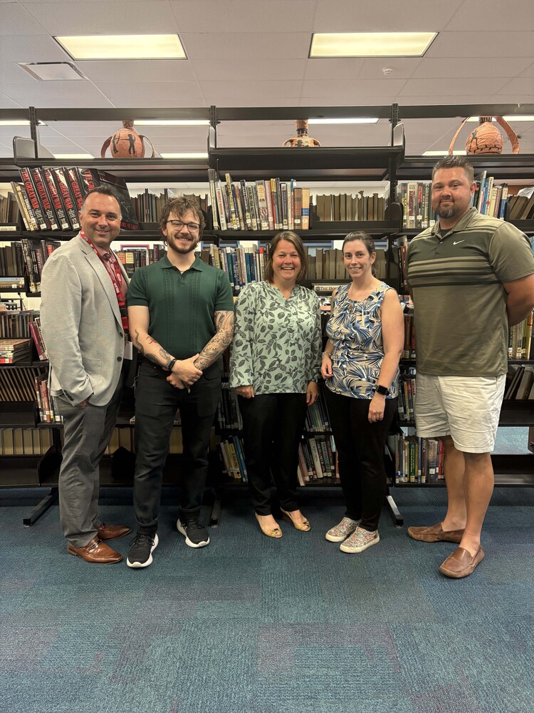 three men and two women pose for photo