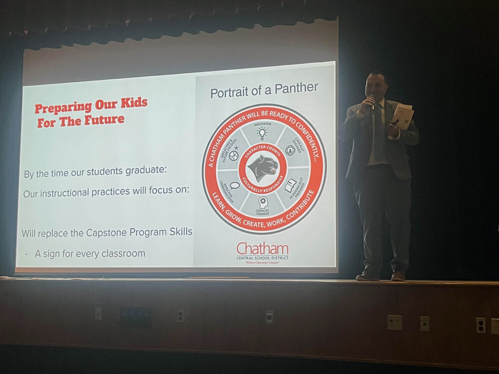 Andrew Kourt speaking next to projector slide  about preparing students for the future
