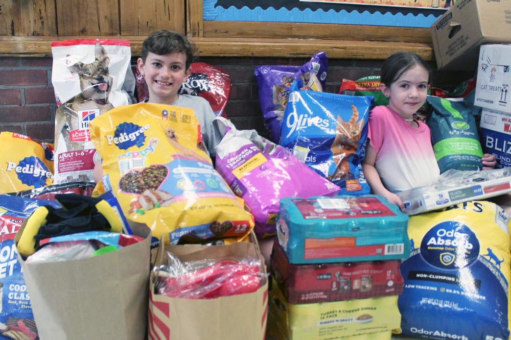 boy and girl sitting amongst big bags of pet food