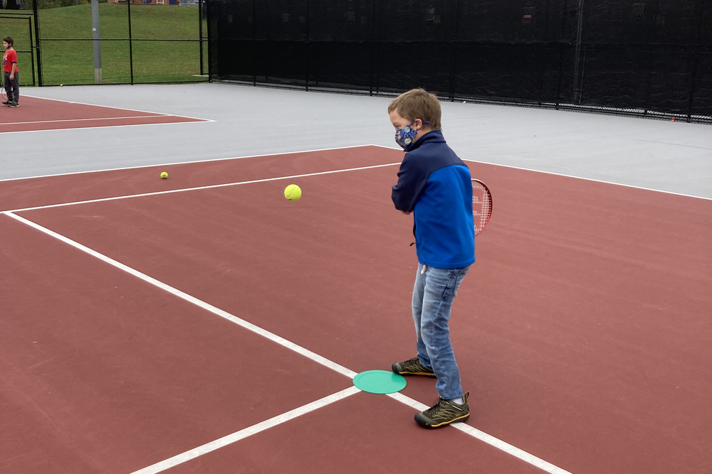 boy swinging racquet at tennis ball