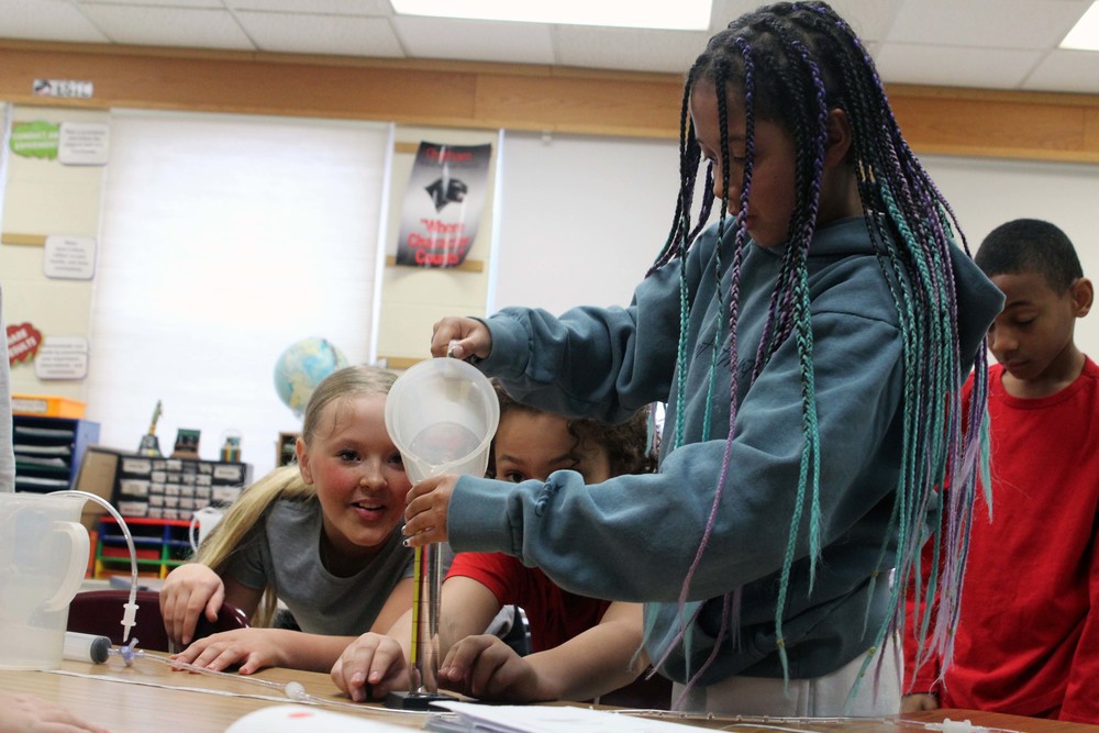 girl pouring water into beaker