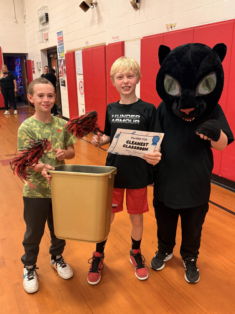 two boys holding golden trashcan next to panther mascot