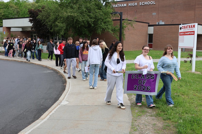 students holding Class of 2026 banner lead line of students out of Chatham High School
