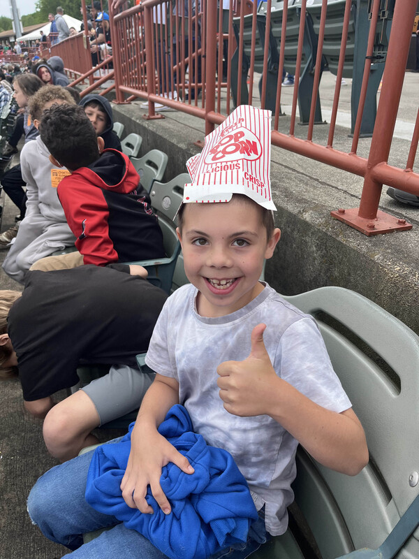 boy with popcorn box on his head giving thumbs up 