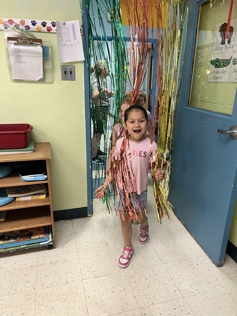 girl passing through beaded curtain into classroom