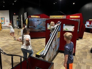 students rolling ball down interactive exhibit