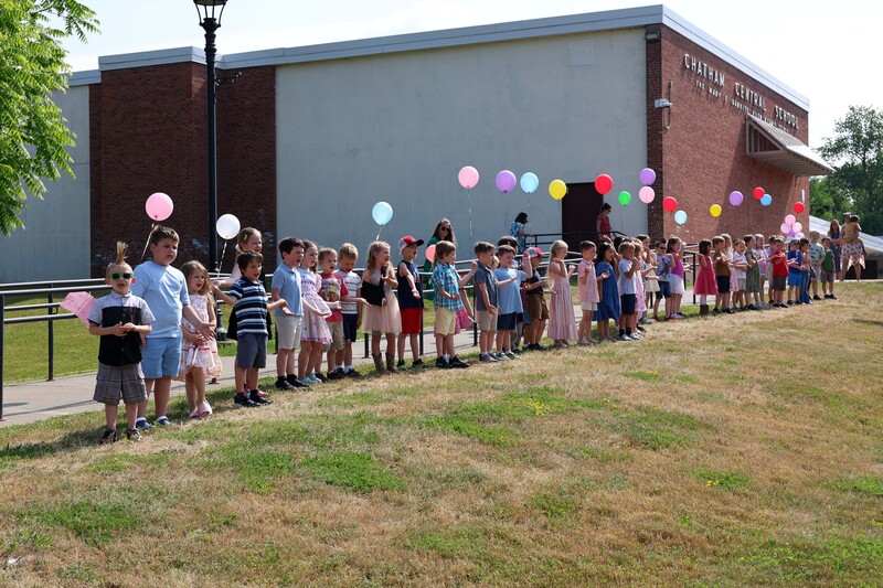 line of students singing songs in front of line of balloons