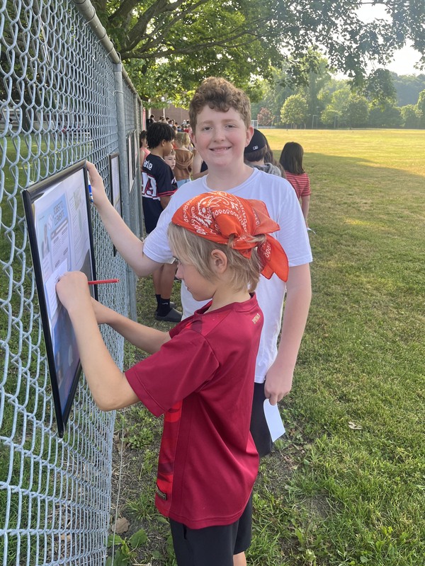 boys writing on poster on fence