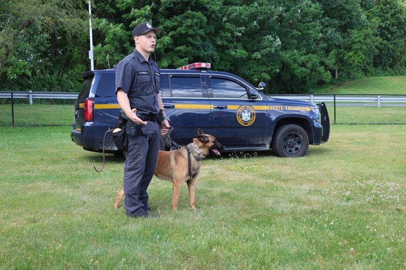 trooper and dog standing in front of NYS Police suv