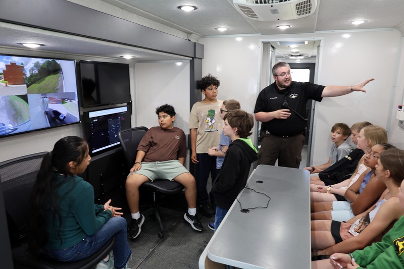 officer showing inside of incident command van to group of students
