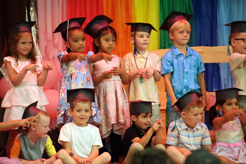 students in graduation caps pointing
