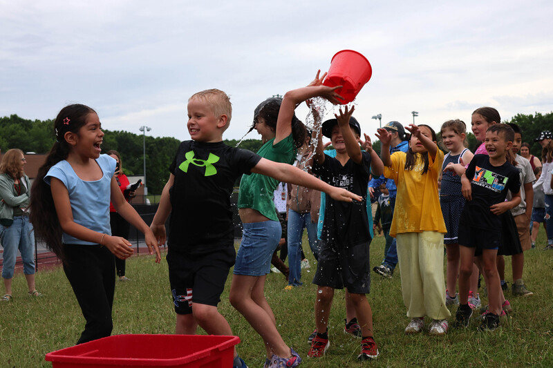 students passing bucket filled with dripping water over their heads