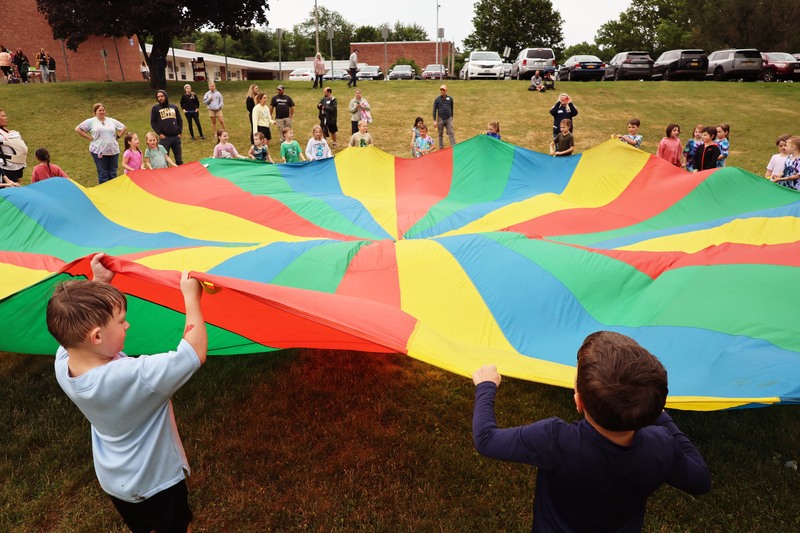 students playing with giant parachute on school lawn