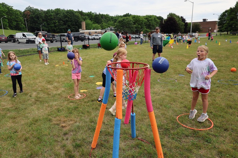 girls tossing balls into basketball hoop set up in middle of field