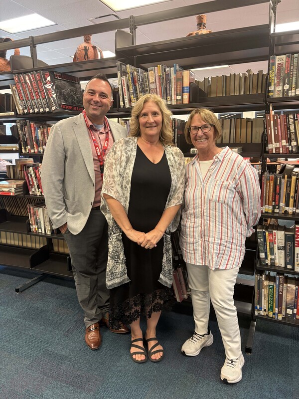 man and two women posing for photo in school library