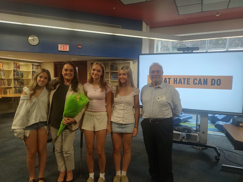 three girls pose with man and woman with flowers