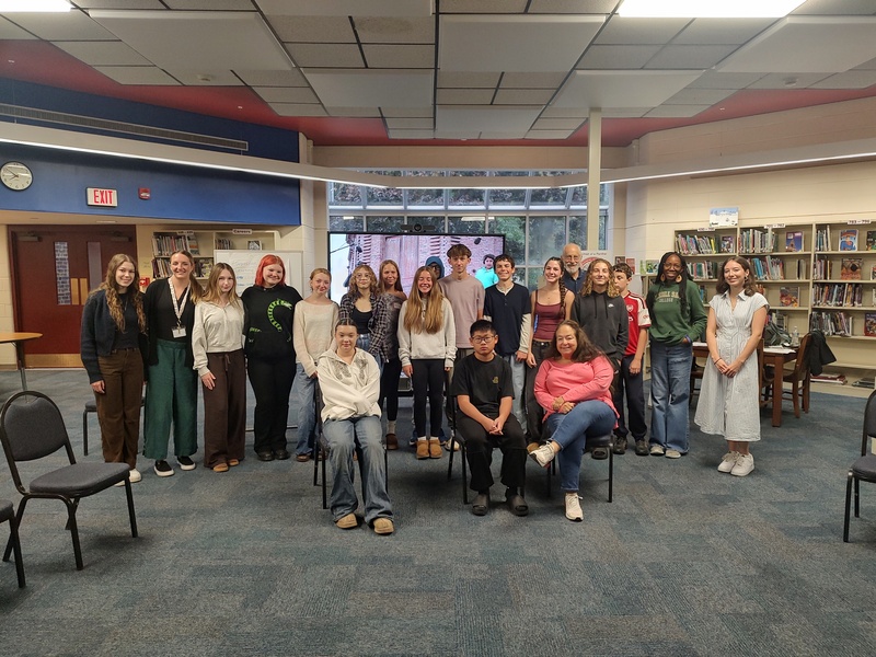 8th grade NCBI trainees, trainers, and CMS school staff pose for group photo in CMS library