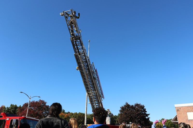 firefighter waving to students from top of ladder
