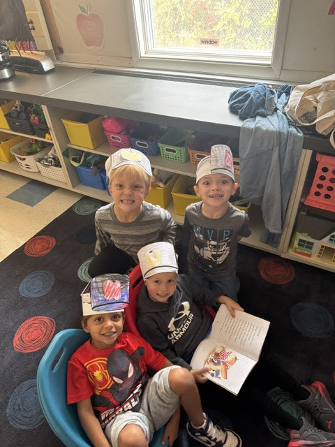 four boys wearing apple hats made from paper