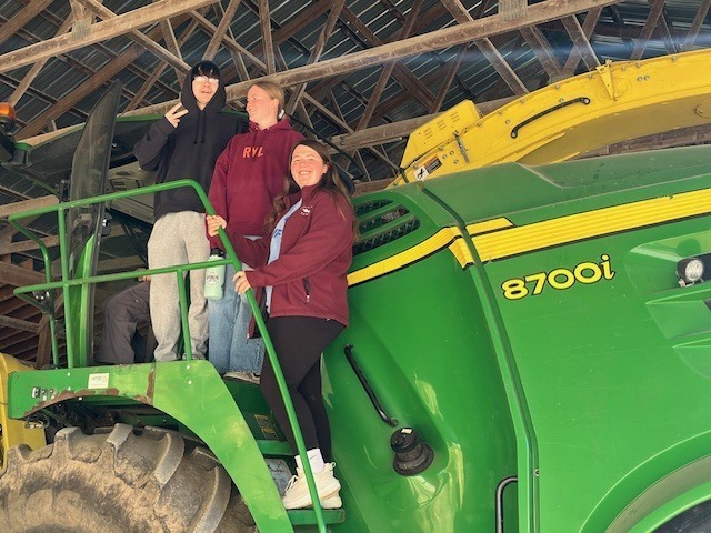 three students on farm combine