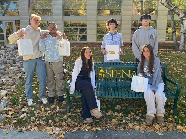 students pose for photo at Siena bench