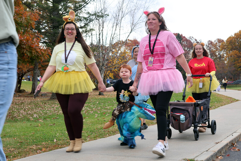 two women holding childs hand dressed in Halloween costumes