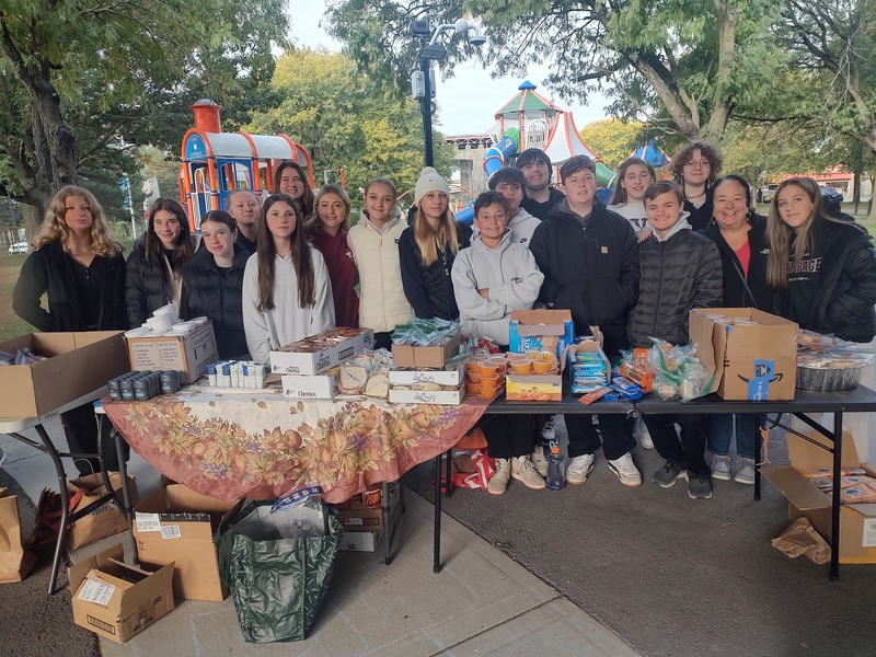 group photos of NHJS and Kiwanis-Service Club students behind tables with food and other essentials on them