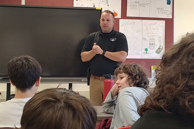 man speaking in front of middle school students