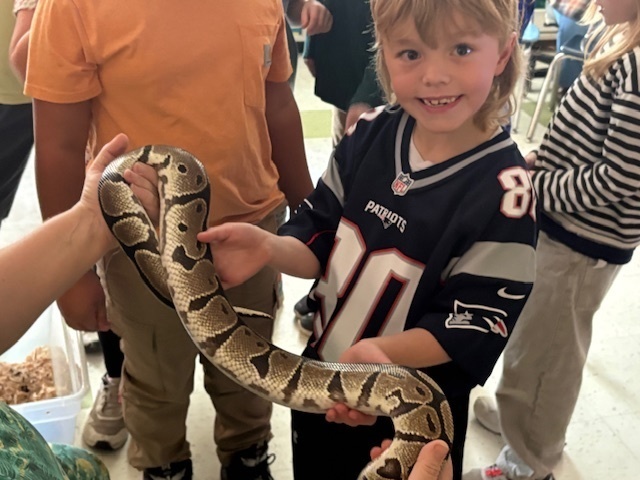 boy touching snake being held by woman