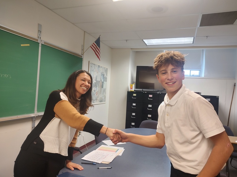 young woman shaking teenage boy's hand