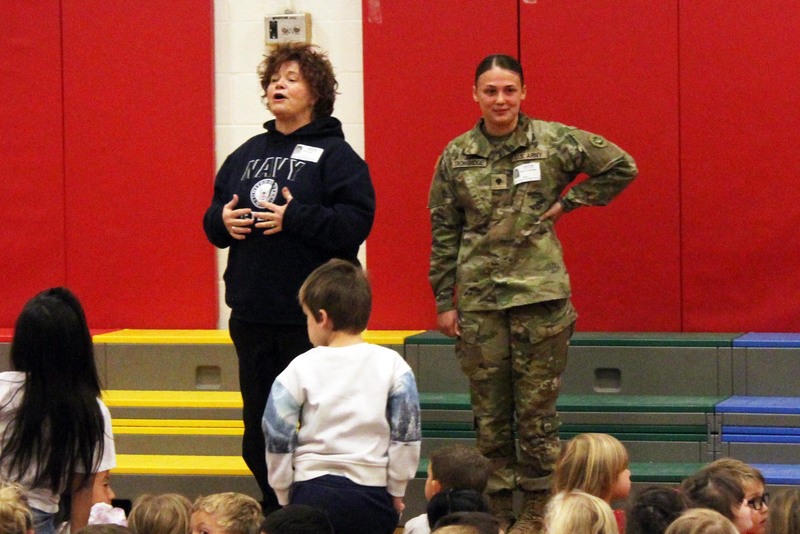 Woman and young woman in army fatigues speaking to audience of students