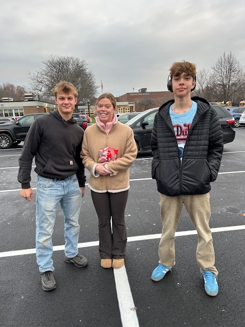 two teenage boys and teenage girl pose for photo in CHS parking lot