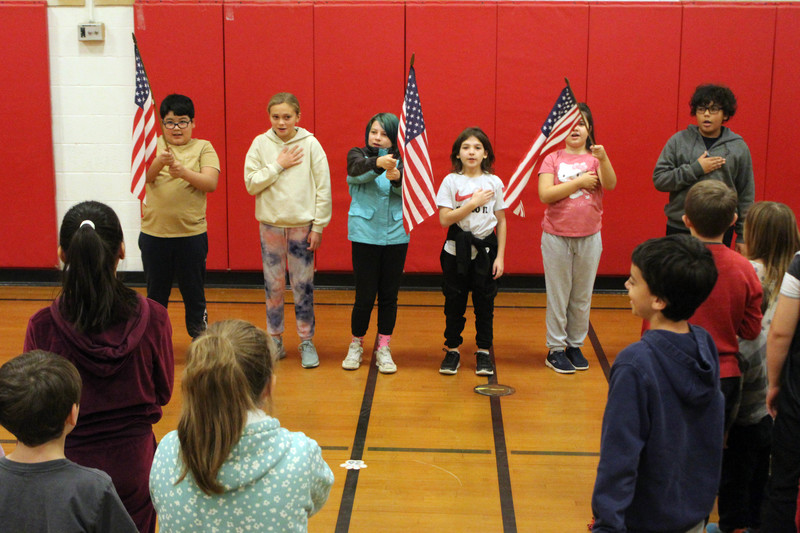 students holding flags reciting the Pledge of Allegiance