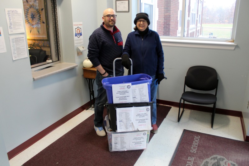 Man and woman pose with boxes on hand cart