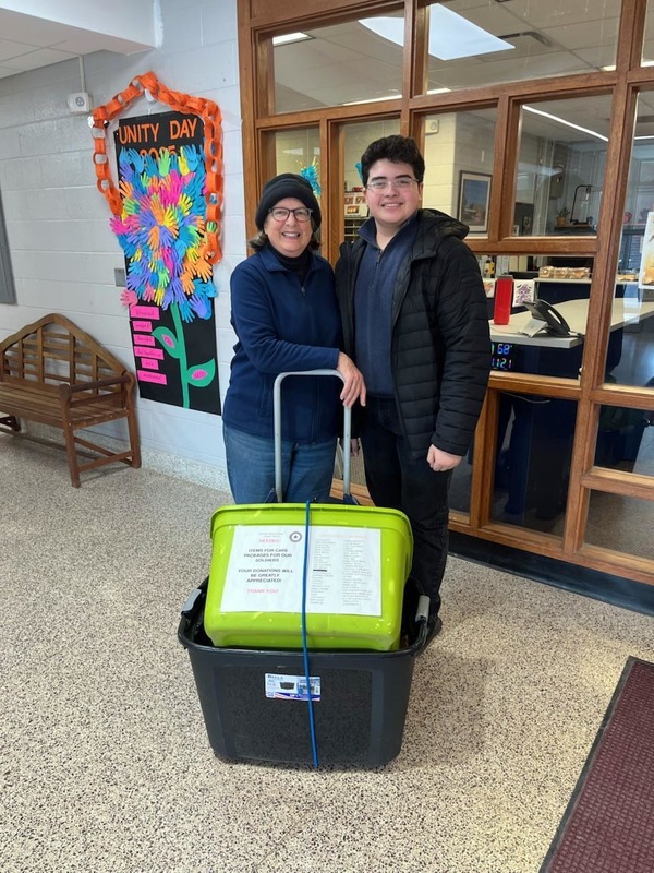 woman and teenage boy pose with boxes on cart