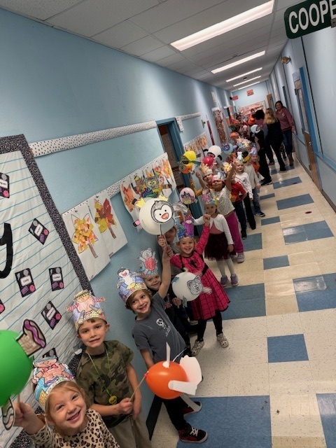 students holding baloons decorated as creatures and walking down the school hallway